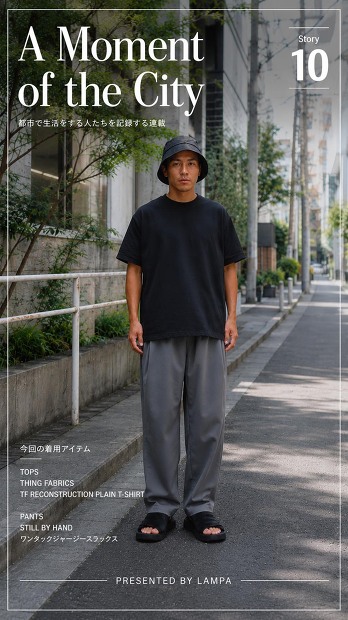 THING FABRICSの黒TシャツとSTILL BY HANDのスラックスを着た男性